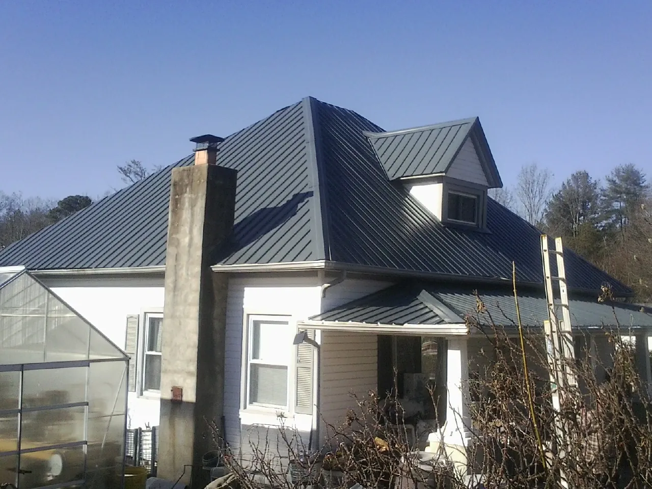 Dark blue standing seam metal roof on a white farmhouse with dormer — Slate & Tile Roof Repair by Roofing Brothers in Keystone Heights