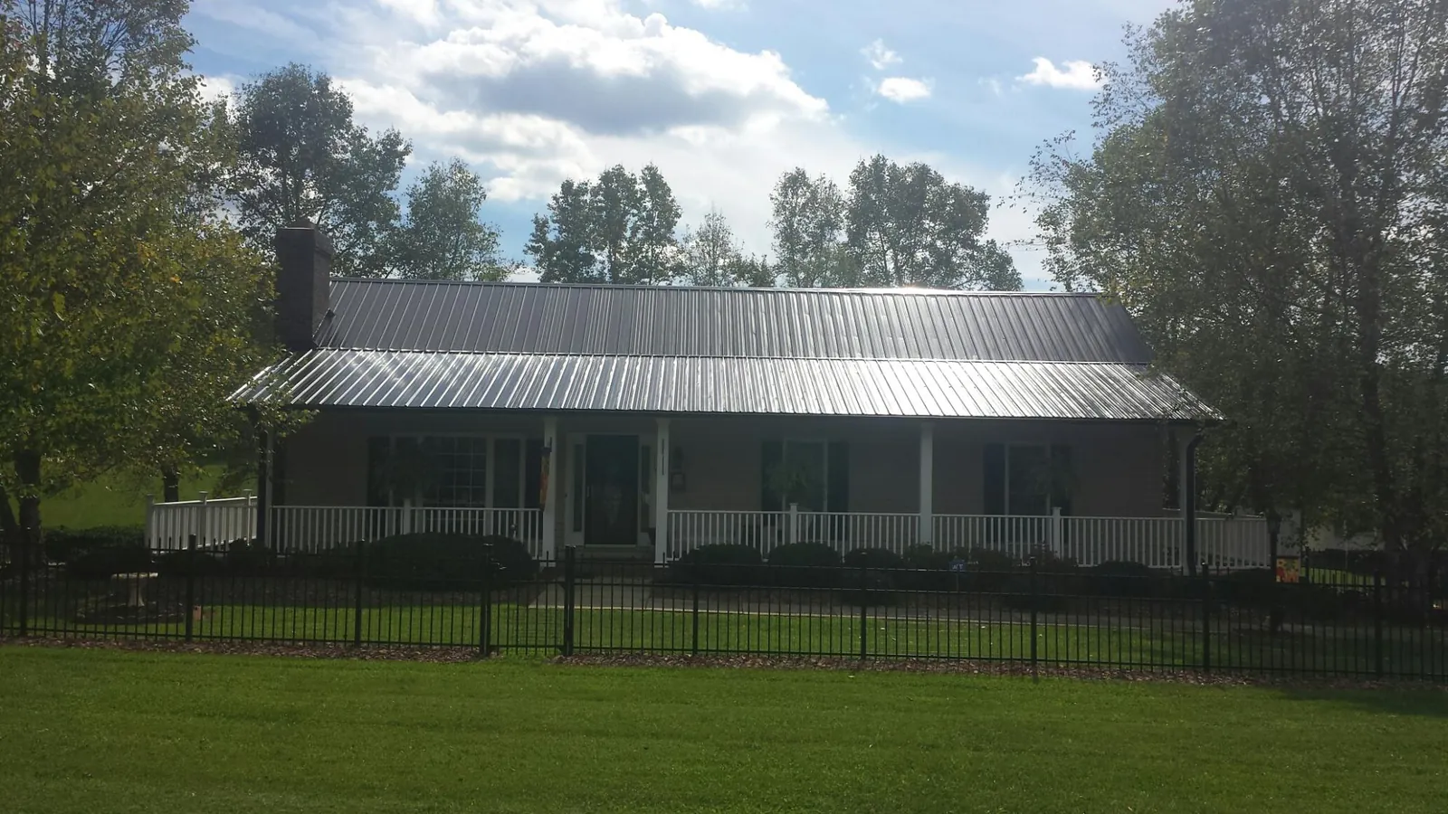 Gray metal roof on a brick ranch with a full width front porch — Gutter Guard Installation work by our crew in Keystone Heights
