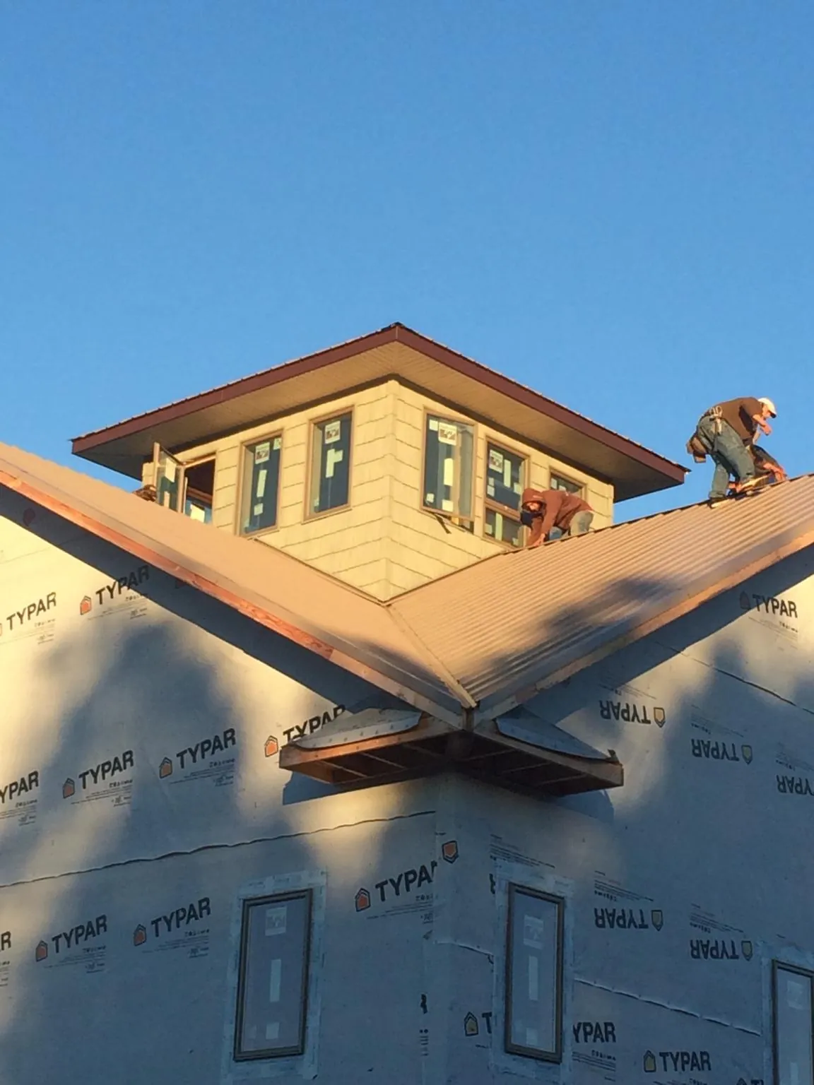 Roofers working around a rooftop cupola on a new metal roof at sunset — Roof Waterproofing in Keystone Heights by Roofing Brothers